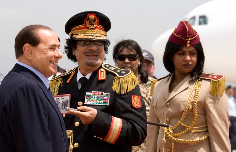 Muammar al-Gaddafi im Oktober 2008 in Roma (Italien) am Flughafen Ciampino mit Silvio Berlusconi und seiner Leibwächterin anösslich eines Staatsbesuchs in Italien